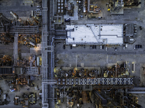 Aerial view of an oil refinery featuring complex piping systems, industrial cooling fans, and storage facilities at dusk, Illinois, United States.