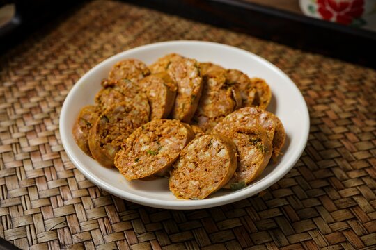 Sliced Northern Thai spicy sausage (Sai Aua) in a white plate on a wooden background