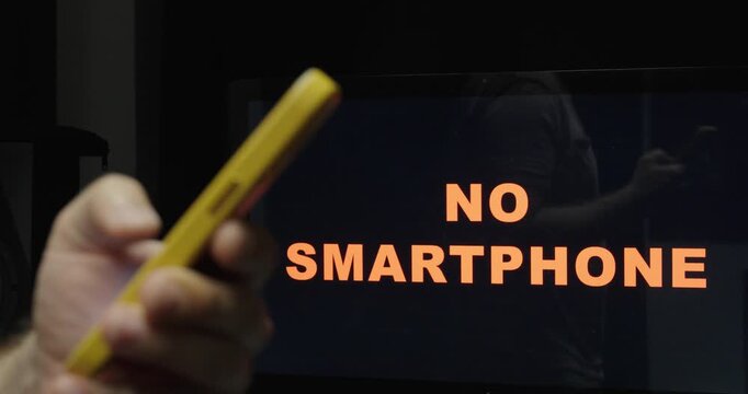 Person holding a smartphone in front of a no smartphone message, illustrating digital detox, smartphone restrictions, and reduced screen time.