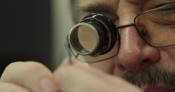 Technician inspecting a small precision component with a jeweler loupe, demonstrating quality control and detailed visual inspection.