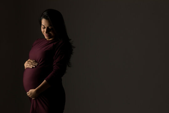 Pregnant woman holding her baby bump in anticipation. 