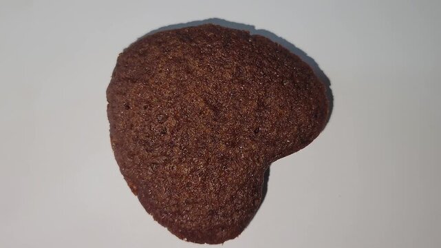Heart-shaped chocolate cookie rotating 360 degrees on white background
