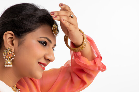 Kathak dancer giving a mesmerising performance in front of a white background and smiling. 