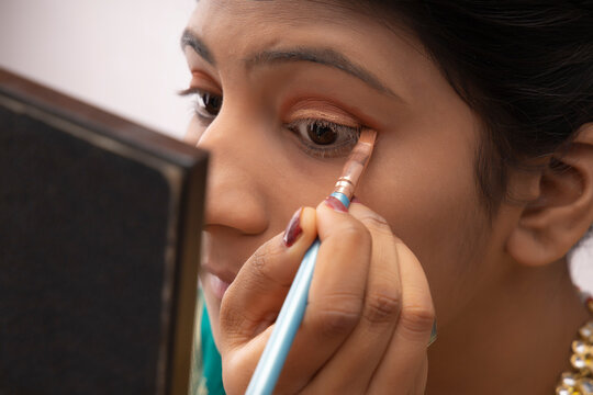 Kathak dancer applying makeup on her face. 