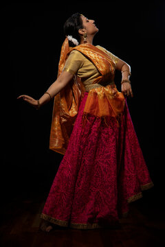Kathak dancer giving a mesmerising performing in front of a dark background. 