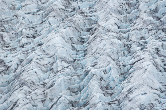 Aerial view of Jokulsarlon glacier ice with deep blue crevasses and textured white ice formations in Iceland.