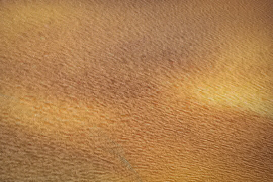 Aerial view of golden textured water surface with gentle ripples creating a rhythmic pattern in Selfoss, Sveitarfelagid Arborg, Iceland.