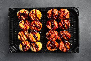 Assorted Japanese sushi rolls topped with fresh salmon shrimp unagi sauce and sesame seeds in takeaway tray. Gourmet seafood set. Tasty fresh Asian food. © Yaruniv-Studio