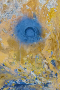 Aerial view of Hverir Sulfur Springs showing vibrant blue geothermal mud pools surrounded by yellow and orange mineral deposits in the volcanic landscape of Reykjahlid, Thingeyjarsveit, Iceland.