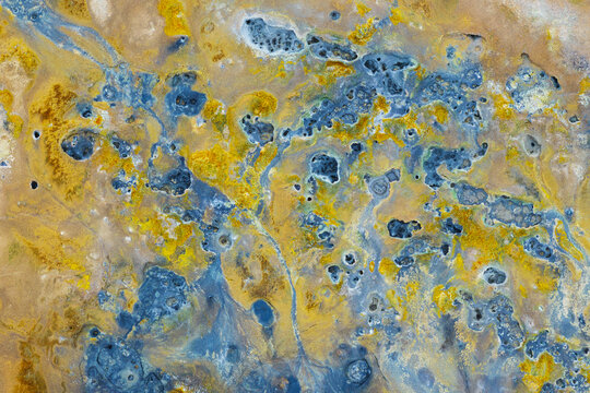 Aerial view of the vibrant blue and yellow mineral deposits and bubbling mud pools at Hverir Sulfur Springs in Reykjahlid, Thingeyjarsveit, Iceland.