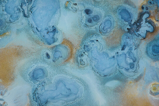 Aerial view of Hverir Sulfur Springs showing vibrant blue geothermal pools, bubbling mud pots, and mineral-rich orange and brown earth textures in Reykjahlid, Thingeyjarsveit, Iceland.