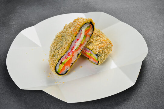 Crispy deep fried sushi sandwich filled with salmon avocado and rice topped with unagi sauce in paper box. Gourmet Japanese takeaway food. Fresh delicious meal.