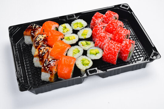Large Japanese sushi roll set with salmon shrimp and unagi eel isolated on white background. Assorted rolls served in black takeaway tray. Fresh seafood.