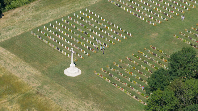 Aerial view of the Thiepval Anglo-French Cemetery with rows of white headstones, a central Cross of Sacrifice, and visitors walking through the grass in Thiepval, Hauts-de-France, France.