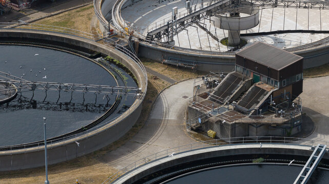 Aerial view of the M Group Water treatment facility featuring large circular sedimentation tanks and industrial infrastructure in Dartford, England, United Kingdom.