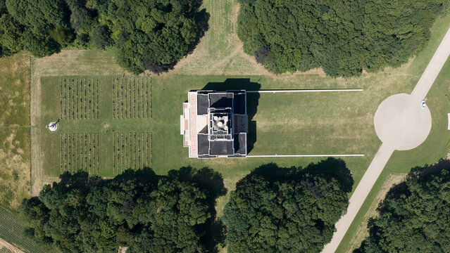 Aerial view of the Thiepval Memorial to the Missing of the Somme surrounded by lush green trees, manicured lawns, and rows of gravestones in Thiepval, Hauts-de-France, France.