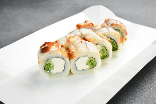 Japanese unagi sushi roll set topped with sweet sauce and sesame seeds. Gourmet rolls filled with cream cheese and cucumber on white background. Tasty food.