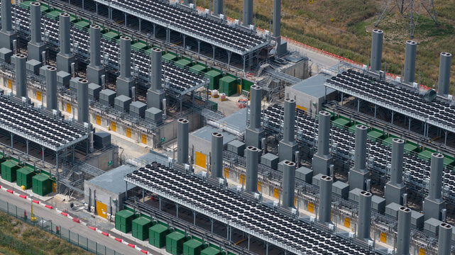 Aerial view of Thurrock Flexible Generation Substation featuring rows of industrial power generation units, cooling fans, and tall exhaust stacks in Tilbury, England, United Kingdom.