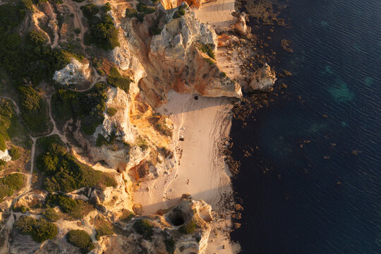 Aerial view of the dramatic golden sandstone cliffs and secluded sandy beach at Ponta da Piedade in Lagos, Faro District, Portugal.