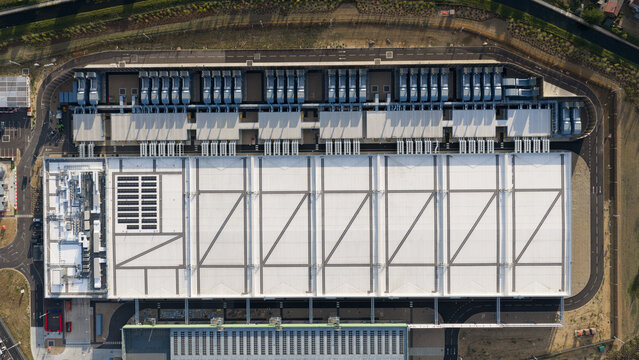 Aerial view of a large industrial data center facility with expansive white rooftops, cooling units, and surrounding paved access roads in Waltham Cross, England, United Kingdom.