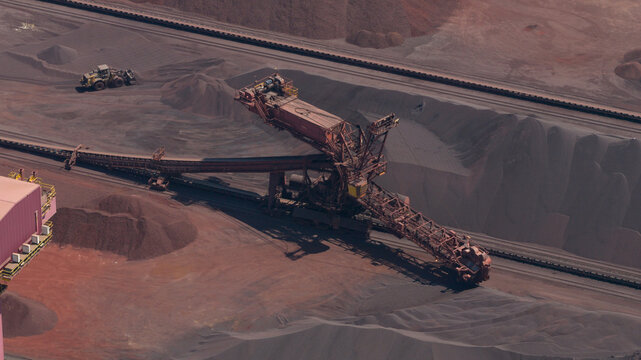 Aerial view of the Cokerie ArcelorMittal industrial site featuring a large stacker-reclaimer machine, piles of raw materials, and conveyor belts in Grande-Synthe, Hauts-de-France, France.