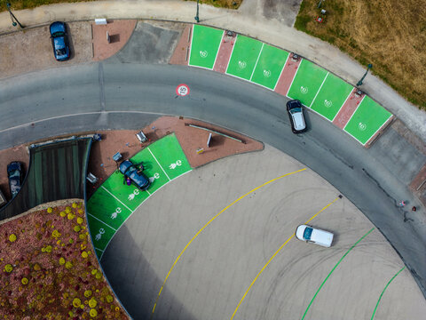 Aerial view of electric vehicle charging station with green parking spaces and cars in Beilen, Drenthe, Netherlands.