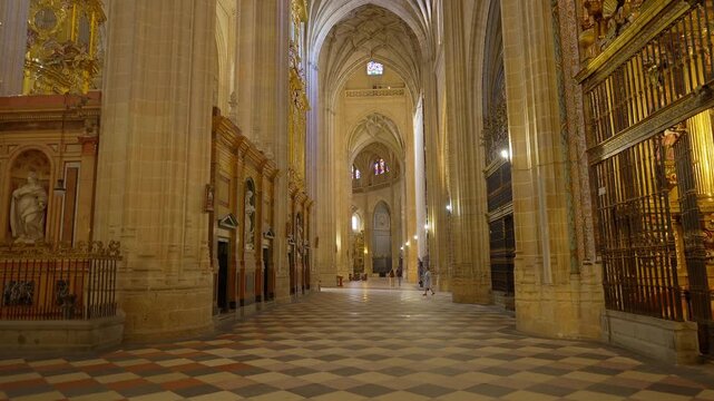 Long cathedral aisle framed by massive stone columns gilded chapels and vaulted arches