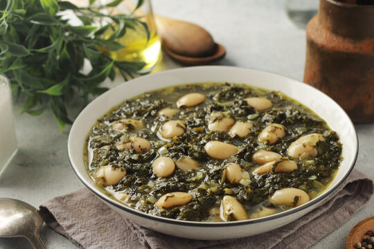 A bowl with traditional Tuscan kale salad and white beans soup Cavolo nero e fagioli