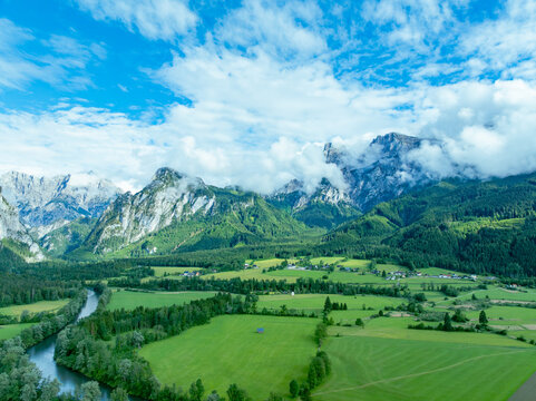Aerial view of Nationalpark Gesause with winding rivers, green valleys, scattered houses, and dramatic mountain peaks such as Admonter Reichenstein and Hochtor in Admont, Steiermark, Austria.