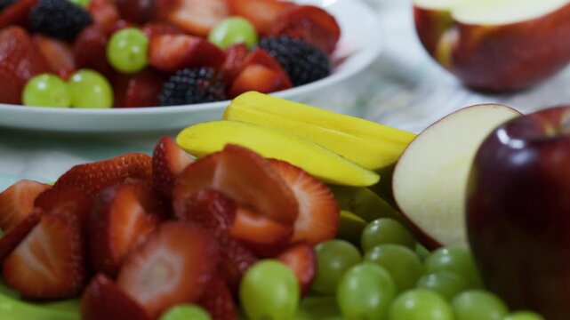 Plates filled with delicious cut and whole fruit on kitchen counter - closeup panning shot