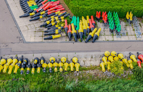 Aerial view of Rijkswaterstaat Harderhaven showing rows of colorful navigation buoys stored on a paved surface near green grass in Zeewolde, Flevoland, Netherlands.