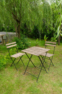 Wooden table and chair set in garden on a sunny day,outdoor seating for restaurant or cafe,Neat paved patio with sitting area and small garden in forest.
