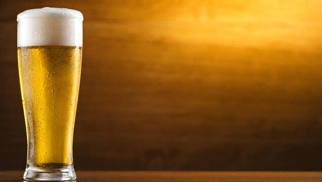 Cold Golden Lager Beer in a Frosted Glass Mug with Rich Foam on a Rustic Wooden Table in a Cozy Bar Setting
