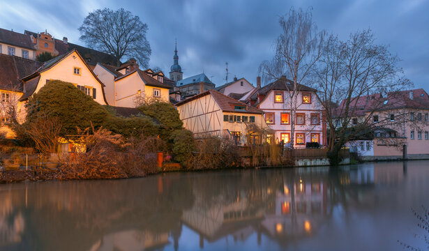 Traditional riverside houses reflected in the Regnitz River during blue hour in the historic center of Bamberg, Bavaria, Germany.