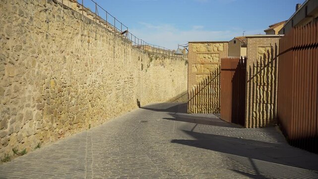 Curving cobblestone lane beside a long historic stone wall in the old quarter of Segovia Spain