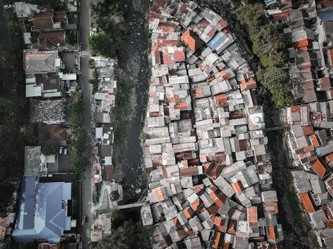Aerial view of the dense urban neighborhood of Baranangsiang with its characteristic rooftops and a river flowing through the area in Bogor Timur, West Java, Indonesia.