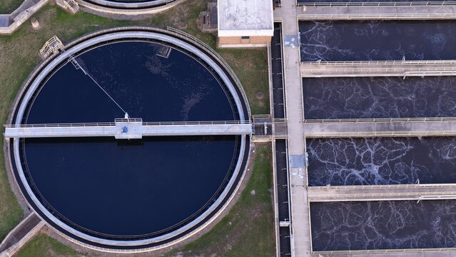 Aerial view of a rural water treatment facility with circular sedimentation tanks and rectangular aeration basins in Monroe, Michigan, United States.