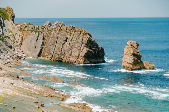 Dramatic rocky cliffs and sea stack towering over the turquoise ocean on Northern Spain coastline. Playa de la Arnia