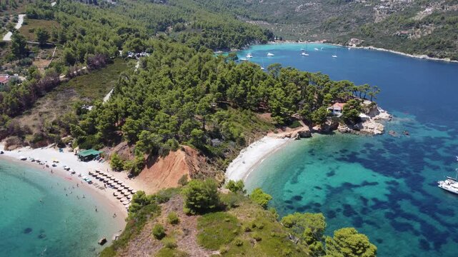 Drone footage of Kokkinokastro Beach on Alonissos Island, Greece, featuring dramatic red cliffs, a secluded sea cave, crystal-clear waters, and lush Mediterranean scenery.