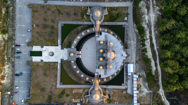Aerial view of the unique circular architecture of Masjid Tiban featuring golden domes and surrounding water features in a peaceful landscape in Bojonegoro, East Java, Indonesia.