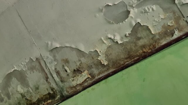 Close up of water damaged ceiling with peeling paint, mold stains and hole needing repair