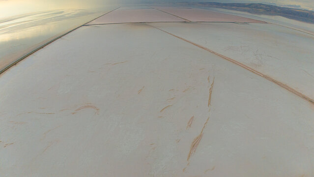 Aerial view of the Koyuncu Salt Works with vast salt flats and pinkish water pools forming geometric patterns in Sereflikochisar, Ankara, Turkiye.
