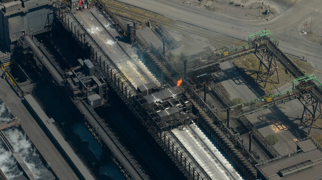 Aerial view of the Cokerie ArcelorMittal industrial facility with smoking chimneys and complex steel infrastructure in Grande-Synthe, Hauts-de-France, France.