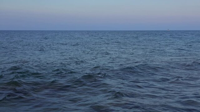 Peaceful ocean waves gently roll under tranquil twilight sky. Distant sailboat adds serene touch to vast seascape. Serene water texture, endless horizon, soft sky colors. Relaxation, travel, nature.