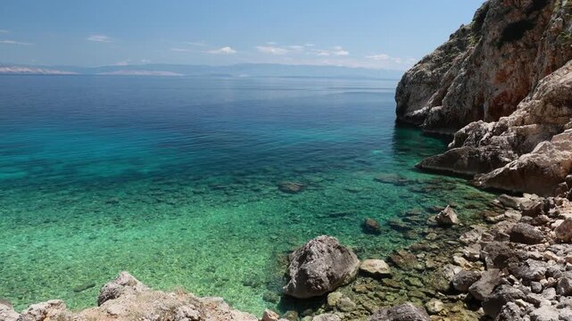 Mali Bok Beach, Cres Island, Croatia. Hidden cove with calm turquoise Adriatic waters, a crystal-clear rocky seabed, and steep limestone cliffs.