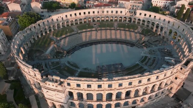 Aerial view of the ancient Roman amphitheater Pula Arena surrounded by historic stone buildings and rooftops in Pula, Istarska zupanija, Croatia.