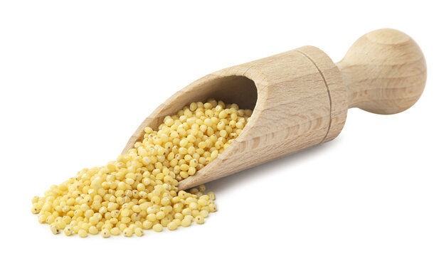 Millet grains pouring from a wooden scoop close-up on a white background. Isolated