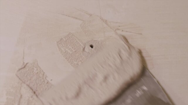 Professional plasterer smoothing drywall compound on wall