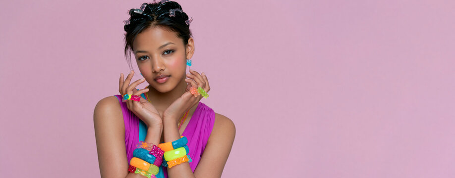 Stylish woman with colorful gummy manicure posing against pink background, playful beauty trend featuring vibrant candy inspired nail art
