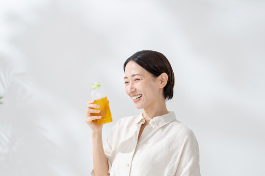 ペットボトルのお茶を飲む女性